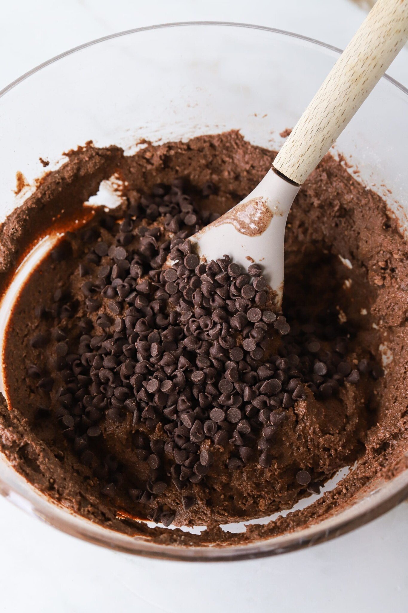 Mini chocolate chips being added to cottage cheese brownie batter.