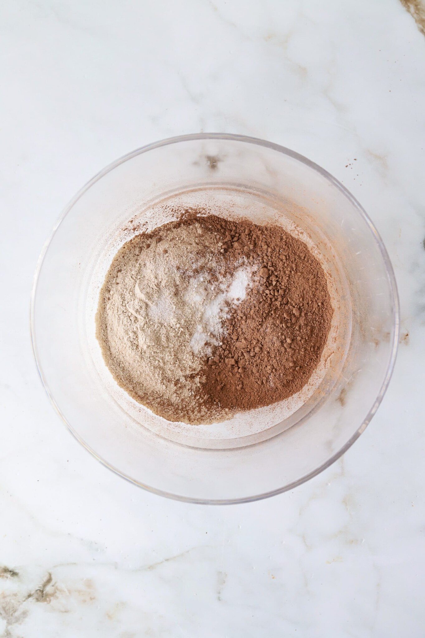 Dry cottage cheese brownie ingredients being poured in a bowl.