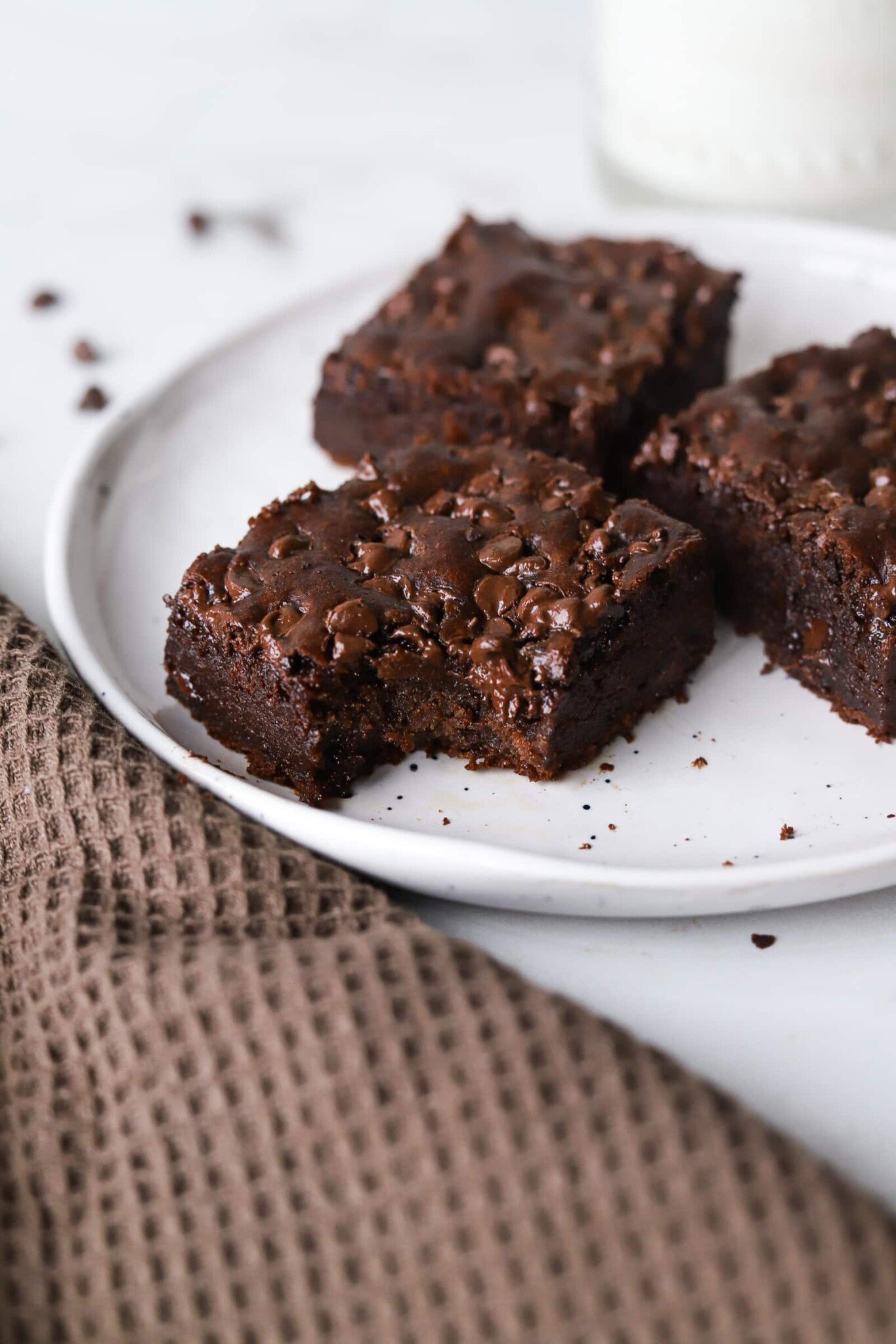 Cottage cheese brownies on a plate with bite taken out of one.