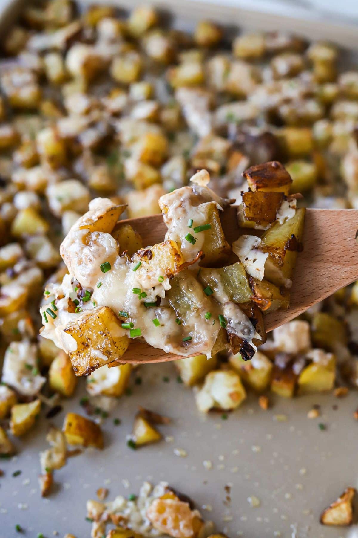 A close up shot of a wooden spoon holding up a scoop of lipton onion soup potatoes.