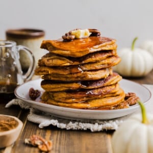 Pumpkin pancakes made with pancake mix stacked on a plate with butter and syrup.