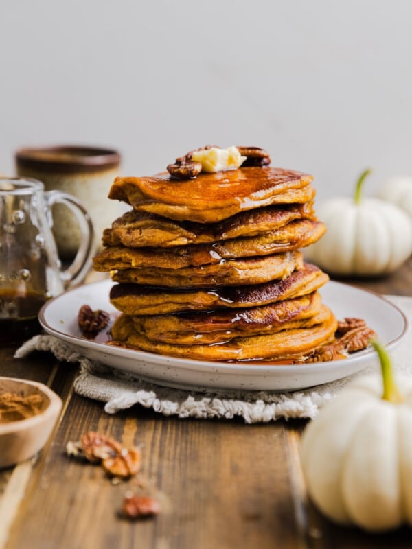 Pumpkin pancakes made with pancake mix stacked on a plate with butter and syrup.