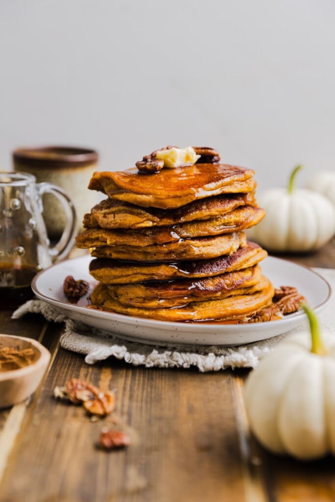 Pumpkin pancakes made with pancake mix stacked on a plate with butter and syrup.