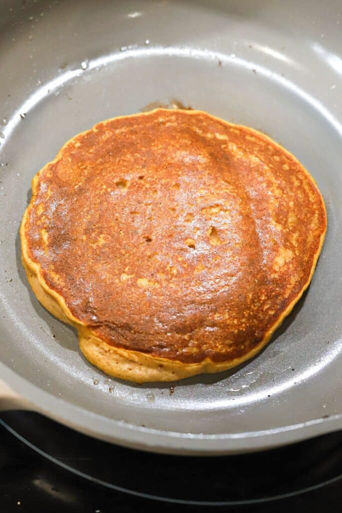 Pumpkin pancakes being cooked in a pan.