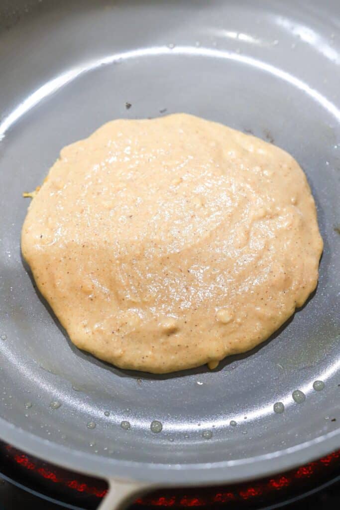 Pumpkin pancakes being cooked in a pan.