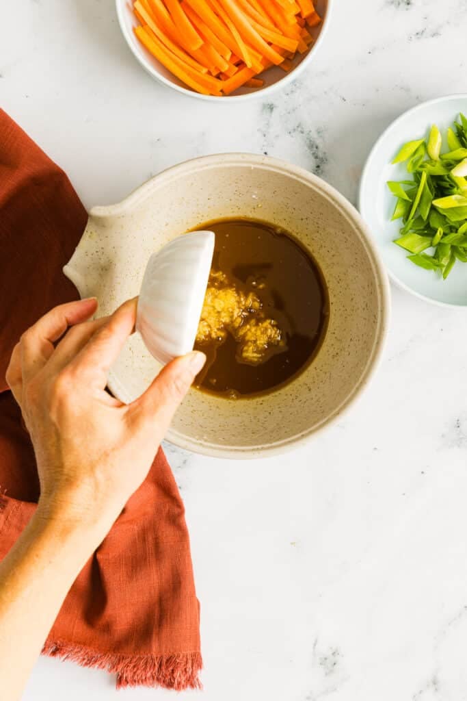 Minced garlic being added to a soy sauce and honey stir-fry sauce.