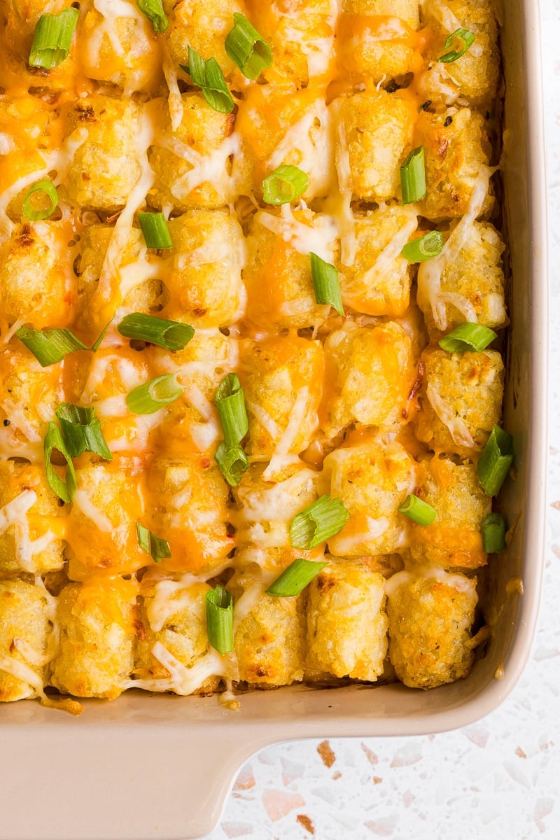 Buffalo chicken tater tot casserole in a baking dish and topped with shredded cheese and green onions.