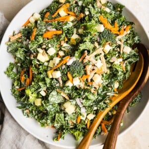 Kale and broccoli salad in a large bowl with wooden salad spoons.
