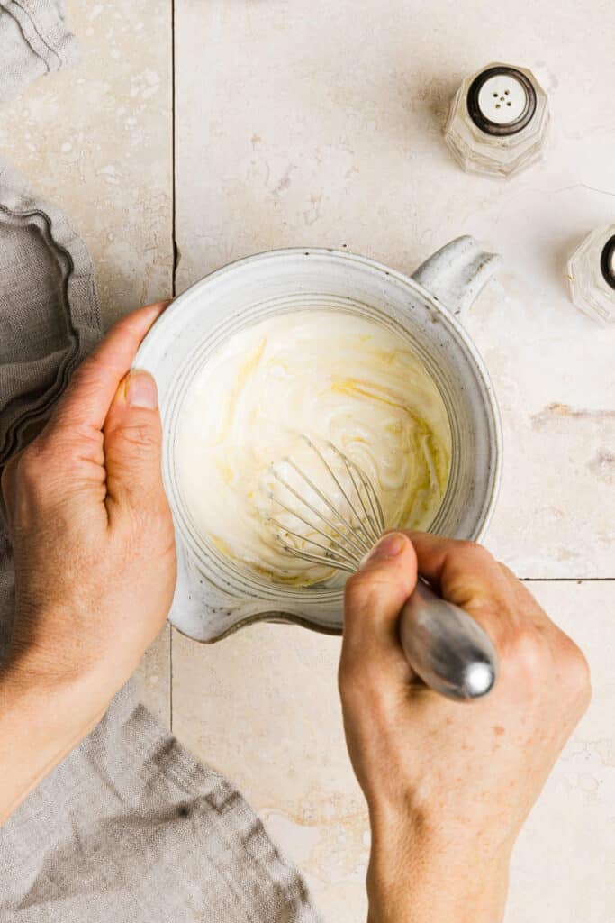 Greek yogurt dressing being whisked in a pitcher.