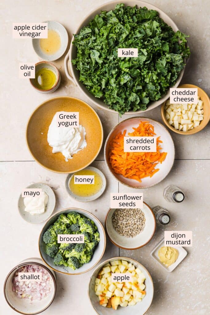 Kale and broccoli salad ingredients on a countertop with labels.