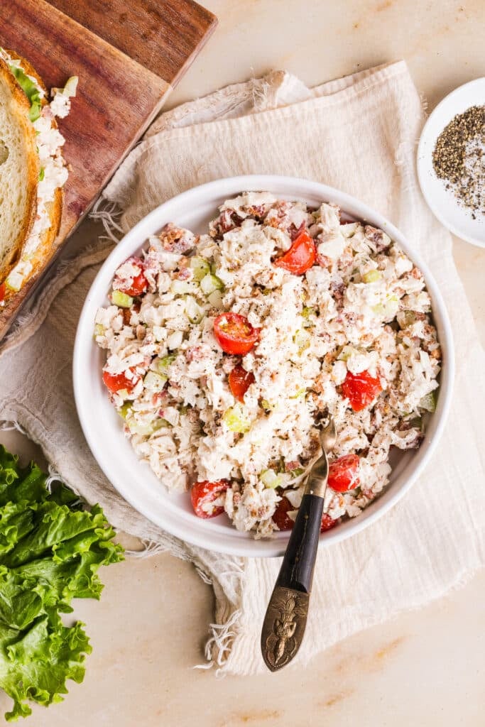 BLT chicken salad in a white bowl with a large spoon.