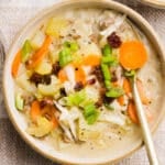 A bowl of creamy hamburger potato soup with crumbled bacon, green onions and cheese.