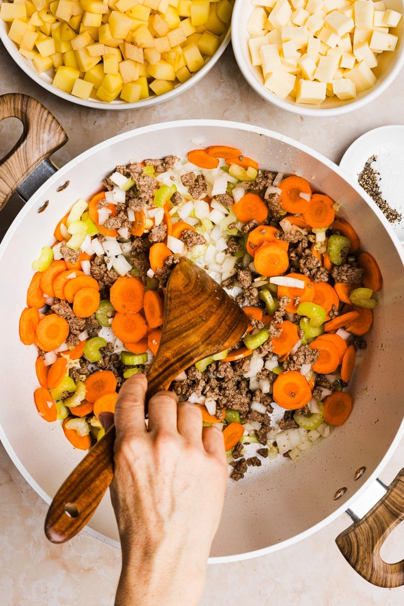 Ground beef, carrots, celery and onion being sauteéd in a large pot.
