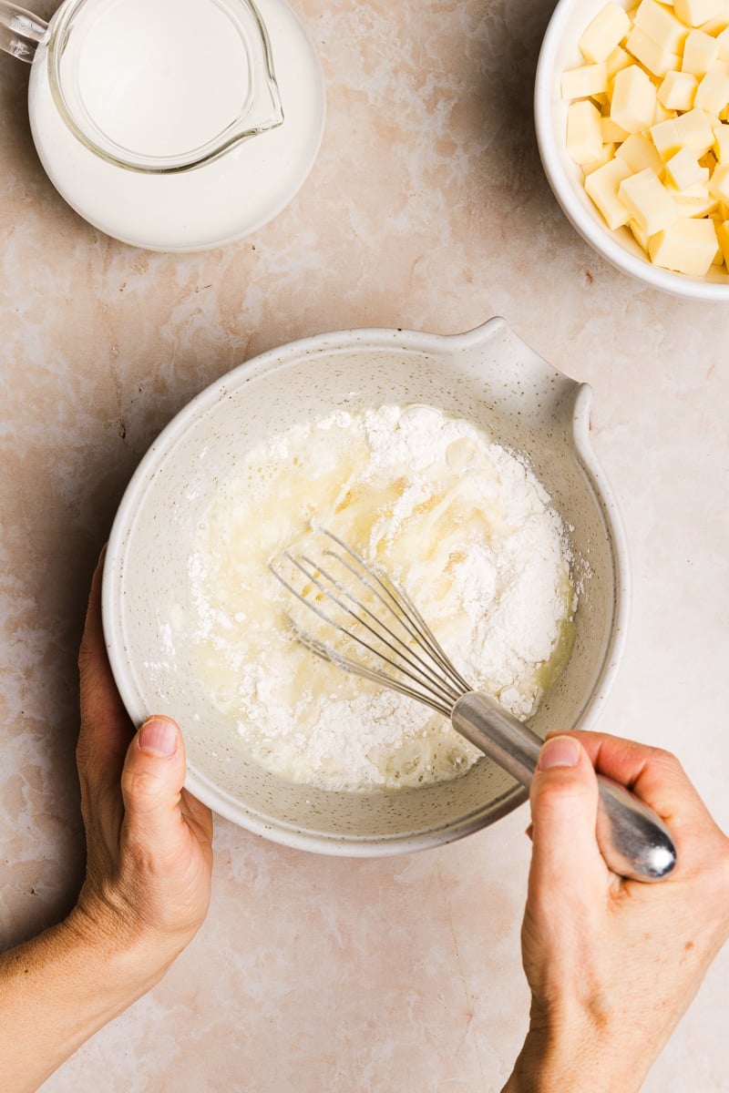 Flour being whisked with milk in a bowl.