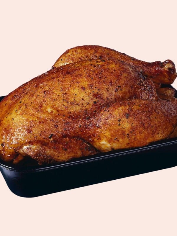 A rotisserie chicken on a pink background.