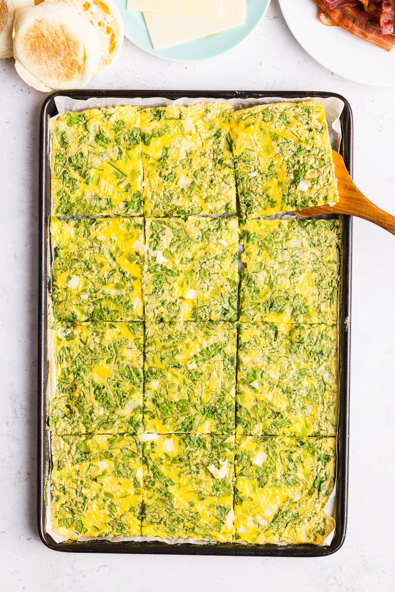 Sheet pan eggs for sandwiches sliced into squares on a sheet pan.