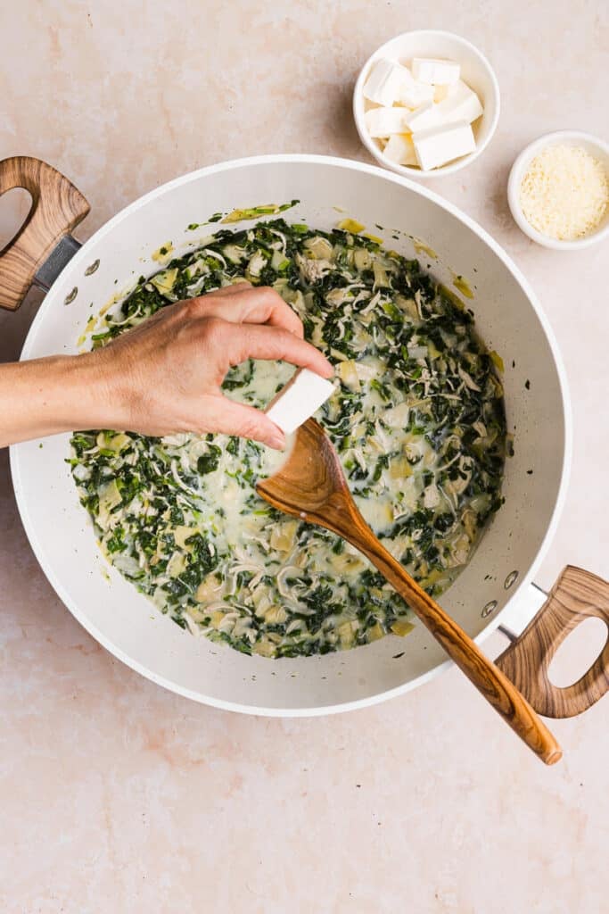 Cream cheese being added to spinach artichoke chicken soup.