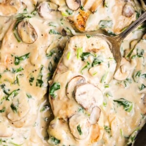 Creamy garlic pork chops in a pan with a large spoon.