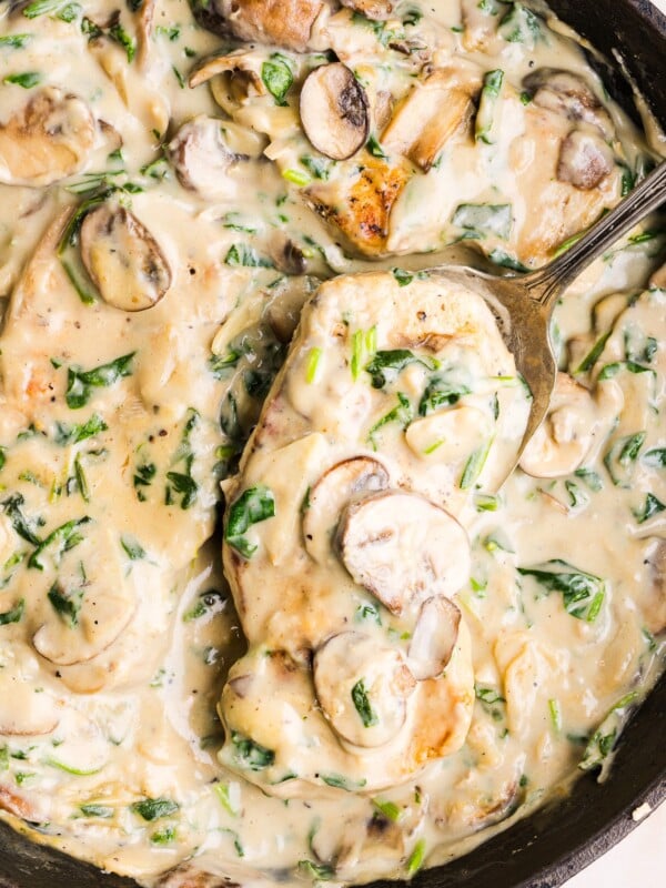 Creamy garlic pork chops in a pan with a large spoon.