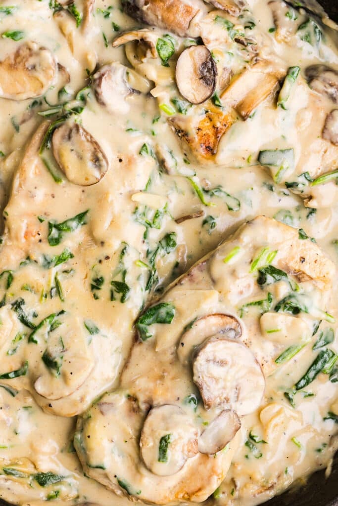 A close up shot of creamy garlic pork chops with spinach and mushrooms.