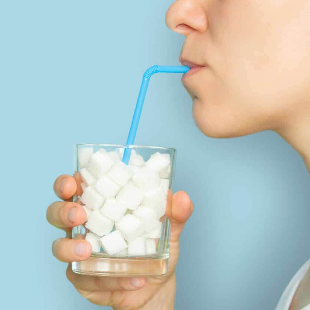 A glass of sugar cubes with a straw.