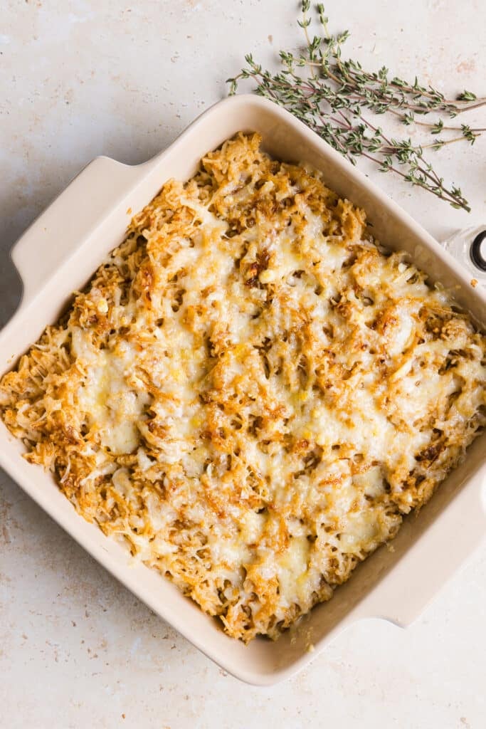 French onion soup mix in a casserole dish topped with gruyère cheese.