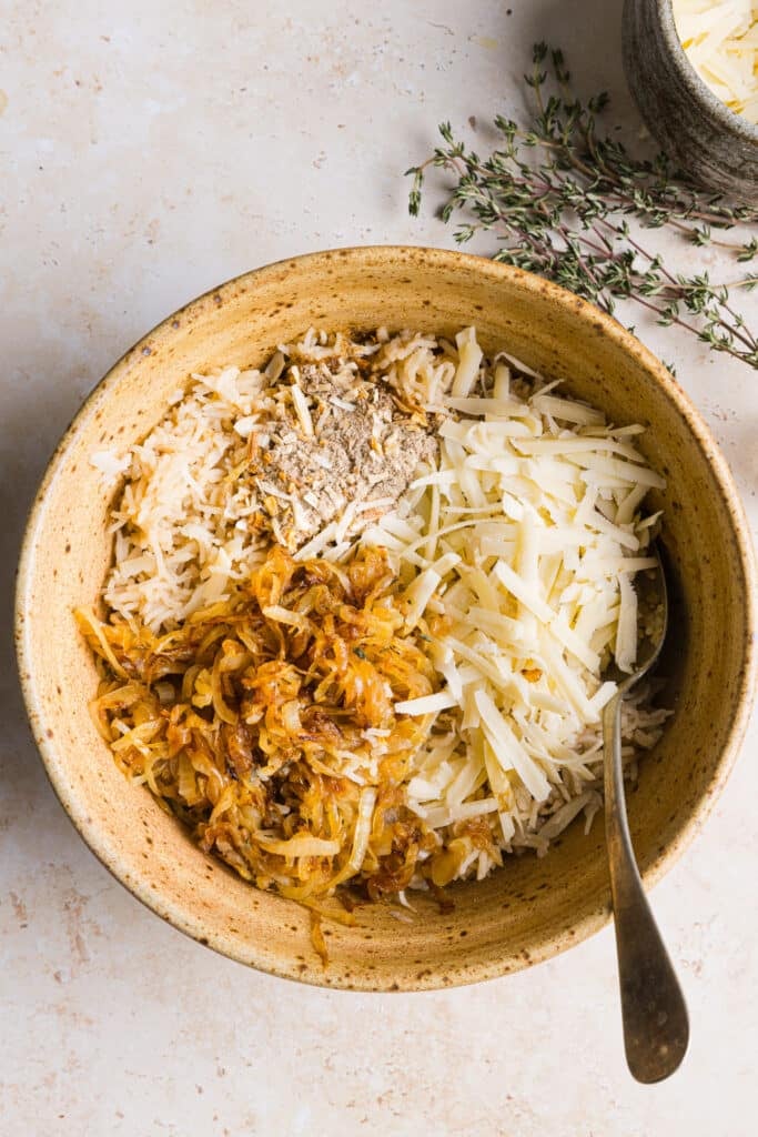 Caramelized onions, cheese and rice being mixed in a bowl.