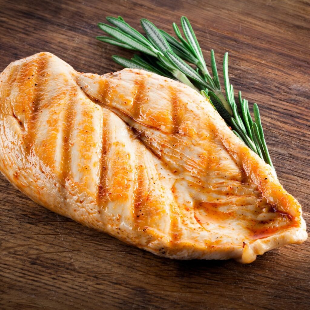 A cooked chicken breast with a sprig of rosemary.