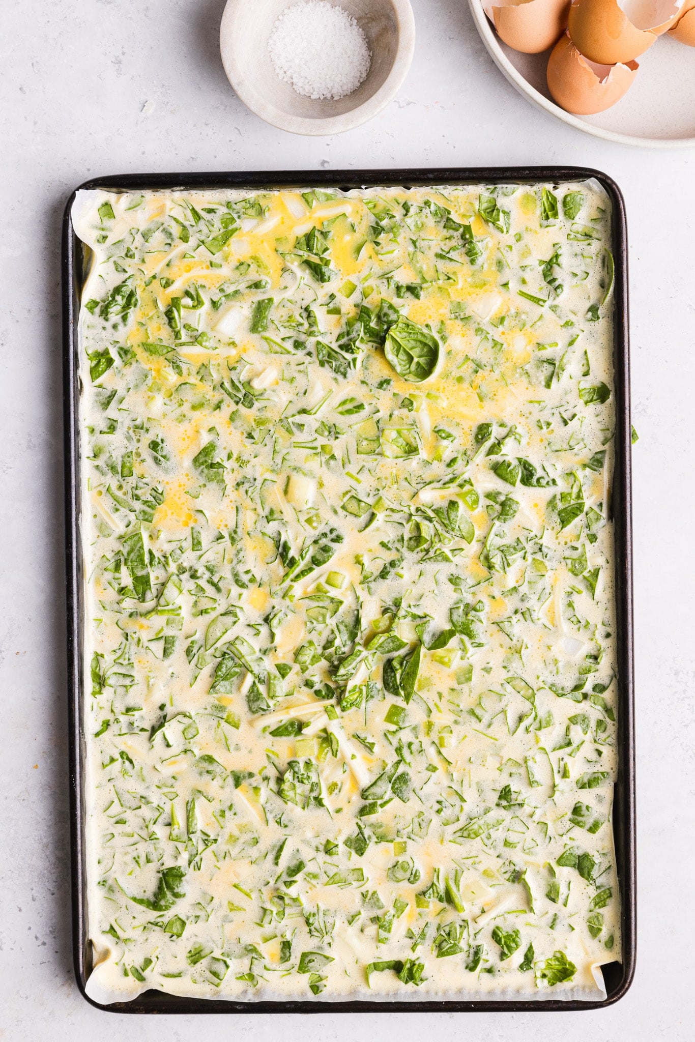 Blended eggs and cottage cheese mixed with veggies in a sheet pan.