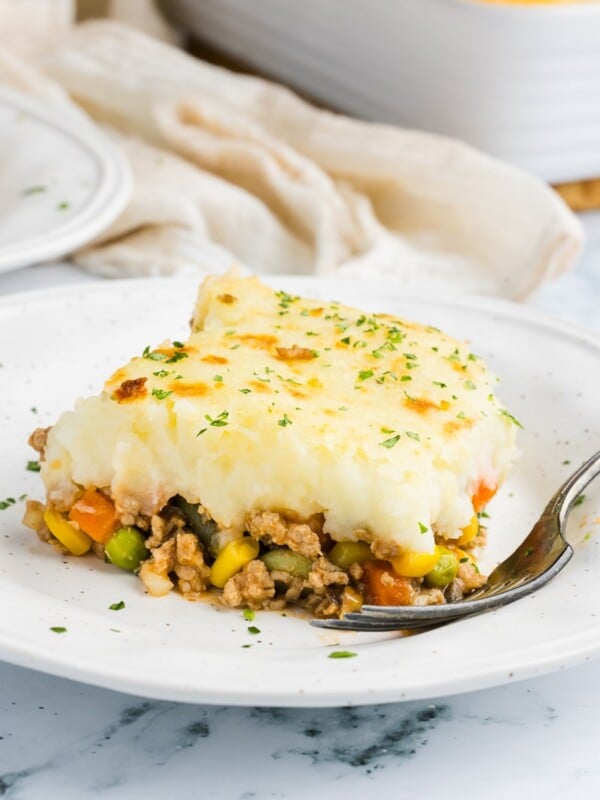 A slice of ground turkey shepherd's pie on a white plate with a fork.