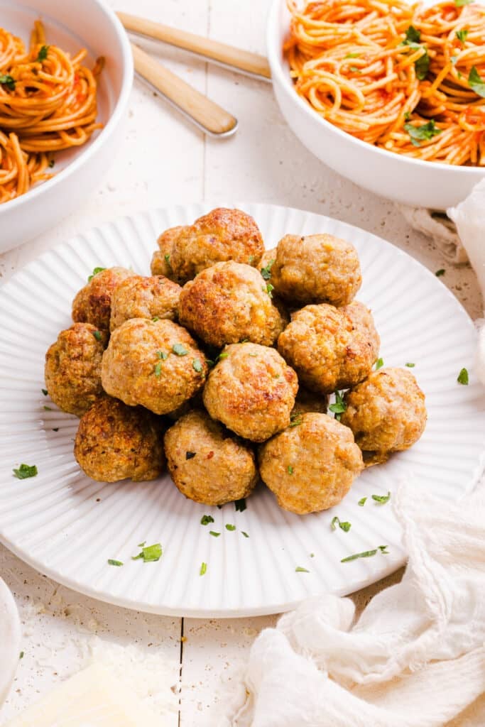 Air fryer turkey meatballs on a white plate with a pasta dish on the side.