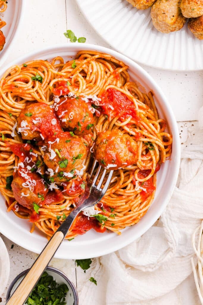 Air fryer turkey meatballs on top of pasta tossed with sauce.