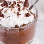 Chocolate blended chia seed pudding in a glass with whipped cream and chocolate shavings.