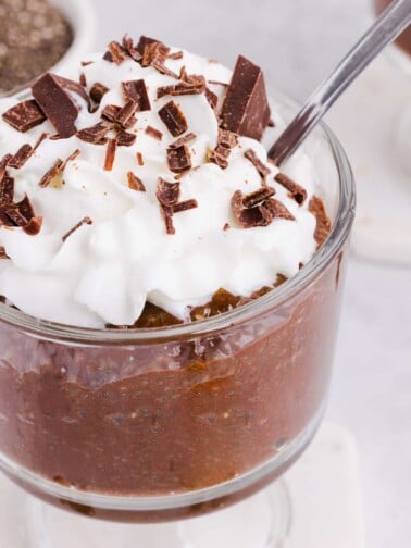 Chocolate blended chia seed pudding in a glass with whipped cream and chocolate shavings.