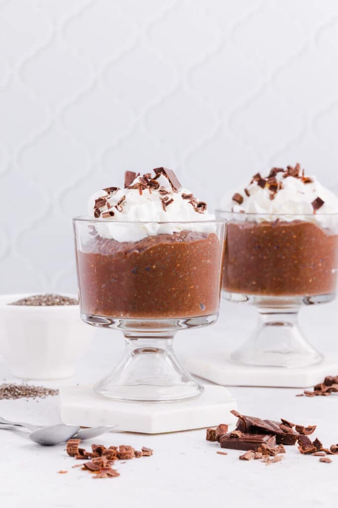 Chocolate blended chia seed pudding in a glass with whipped cream and chocolate shavings.