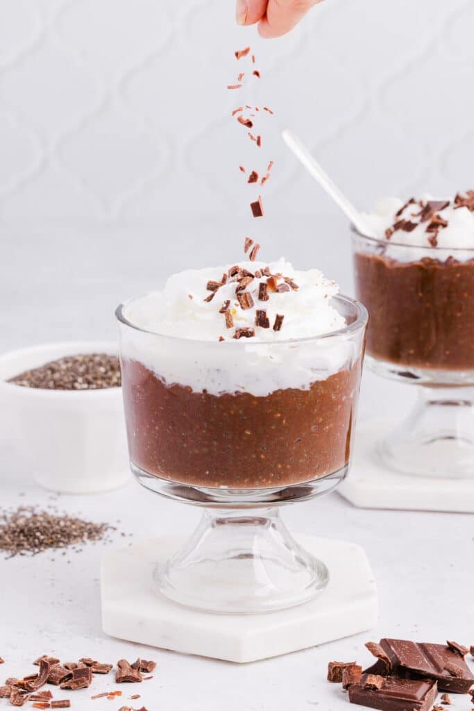 Chocolate shavings being sprinkled on top of blended chocolate chia seed pudding.