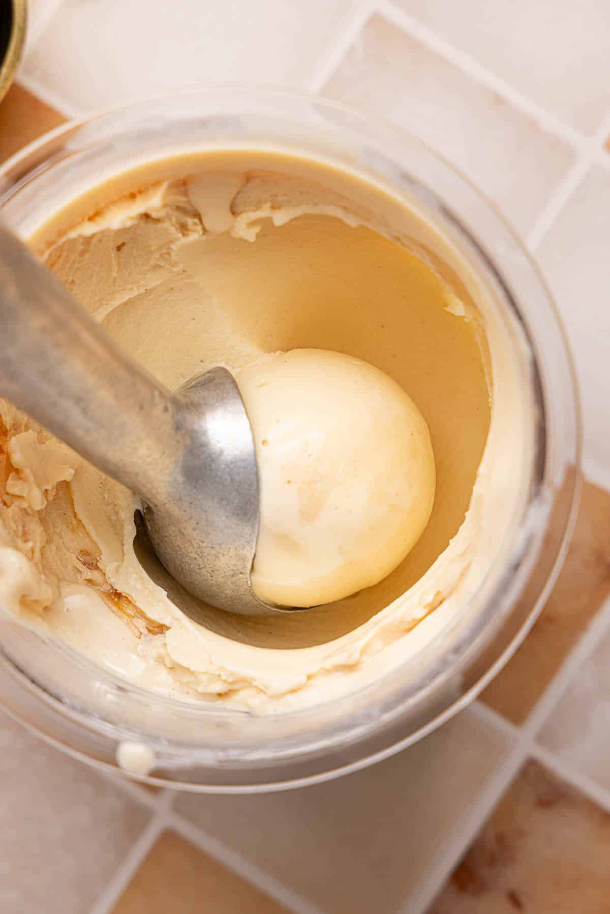 An ice cream scoop scoops peanut butter ice cream from the ninja creami container.