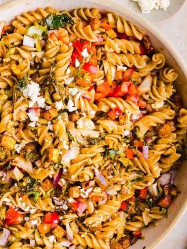 A close up shot of winter pasta salad in a large serving bowl.