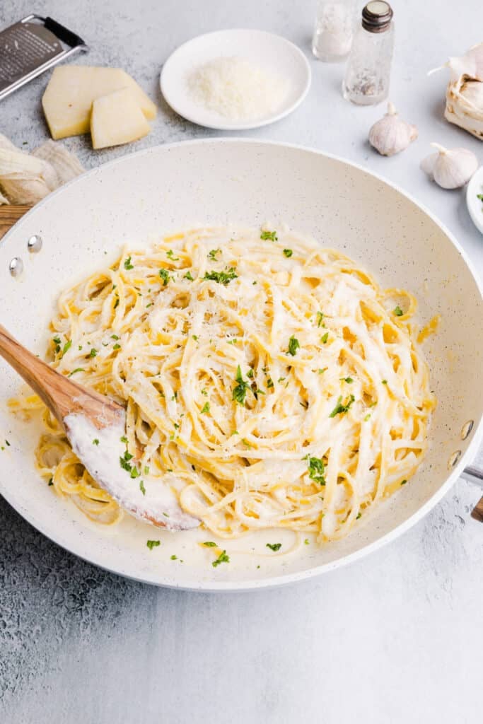 Greek yogurt Alfredo sauce in a pan with a wooden spoon.