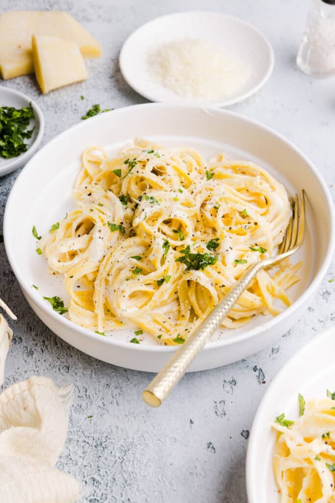 Greek yogurt Alfredo sauce in a shallow bowl garnished with parsley.