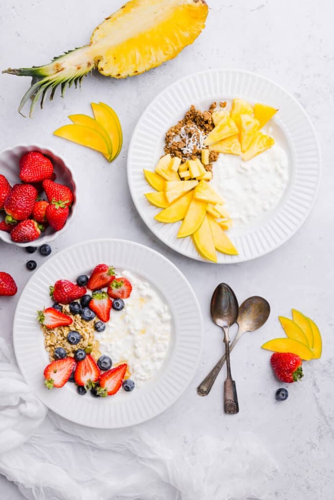 Cottage cheese and fruit bowls with various toppings like berries, granola, pineapple and mango.