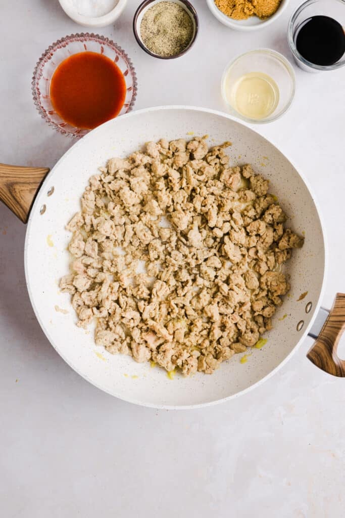 Ground chicken added to a pan with garlic and ginger.