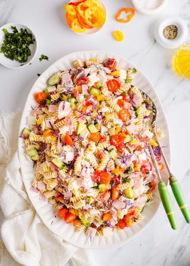 Grinder pasta salad on a large white platter with two serving spoons.