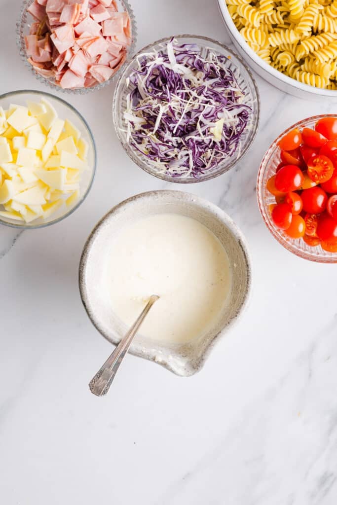 Grinder pasta salad dressing mixed up in a small bowl with a spoon.
