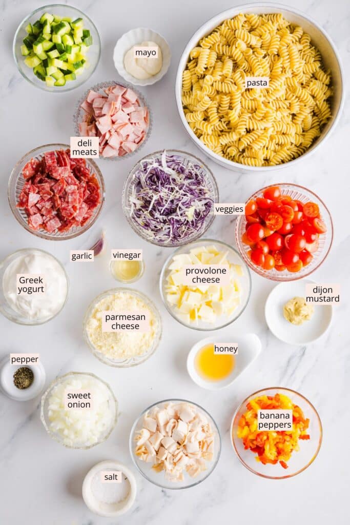 Ingredients for grinder pasta salad on a countertop with labels.