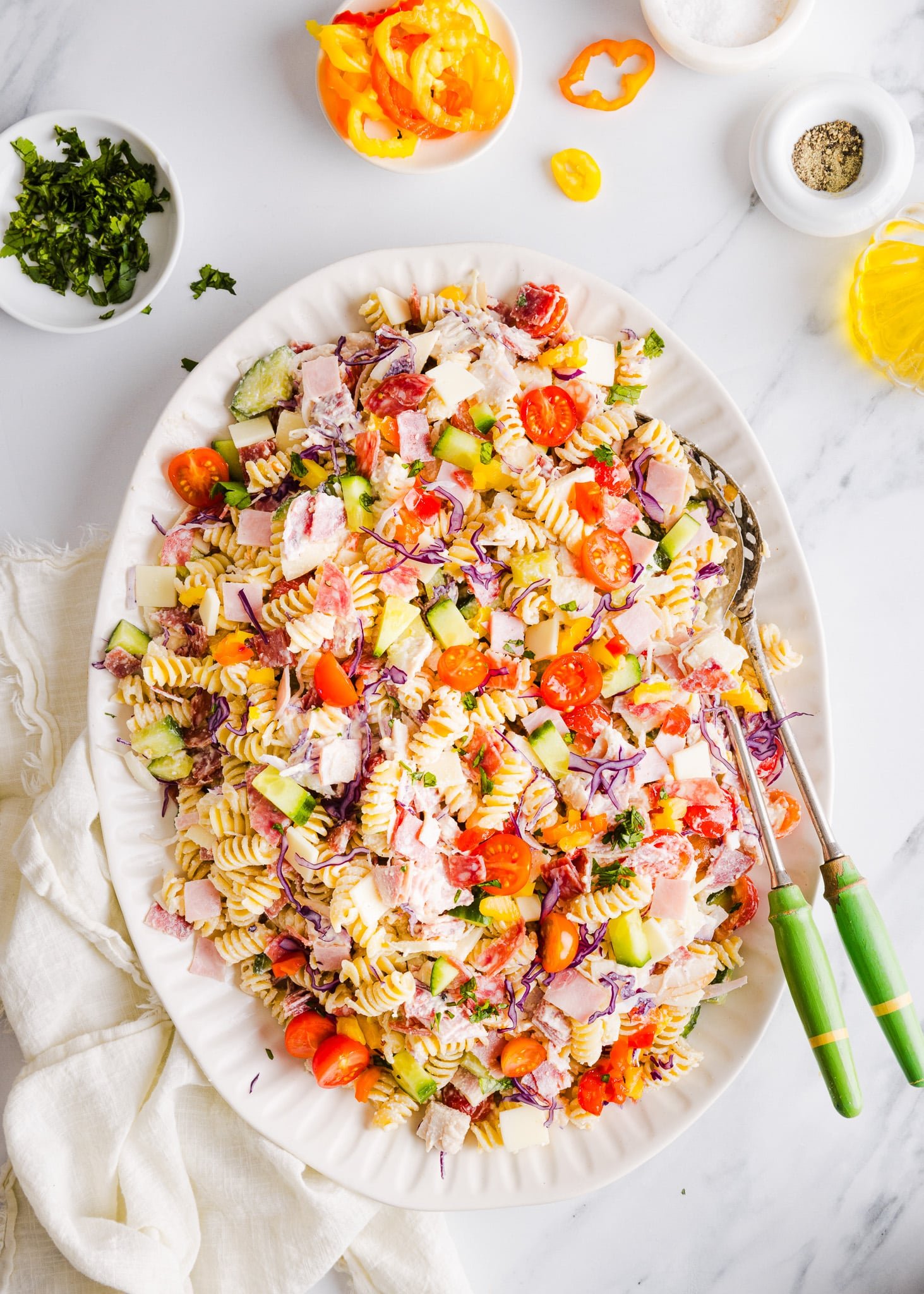 Grinder pasta salad on a large white platter with two serving spoons.