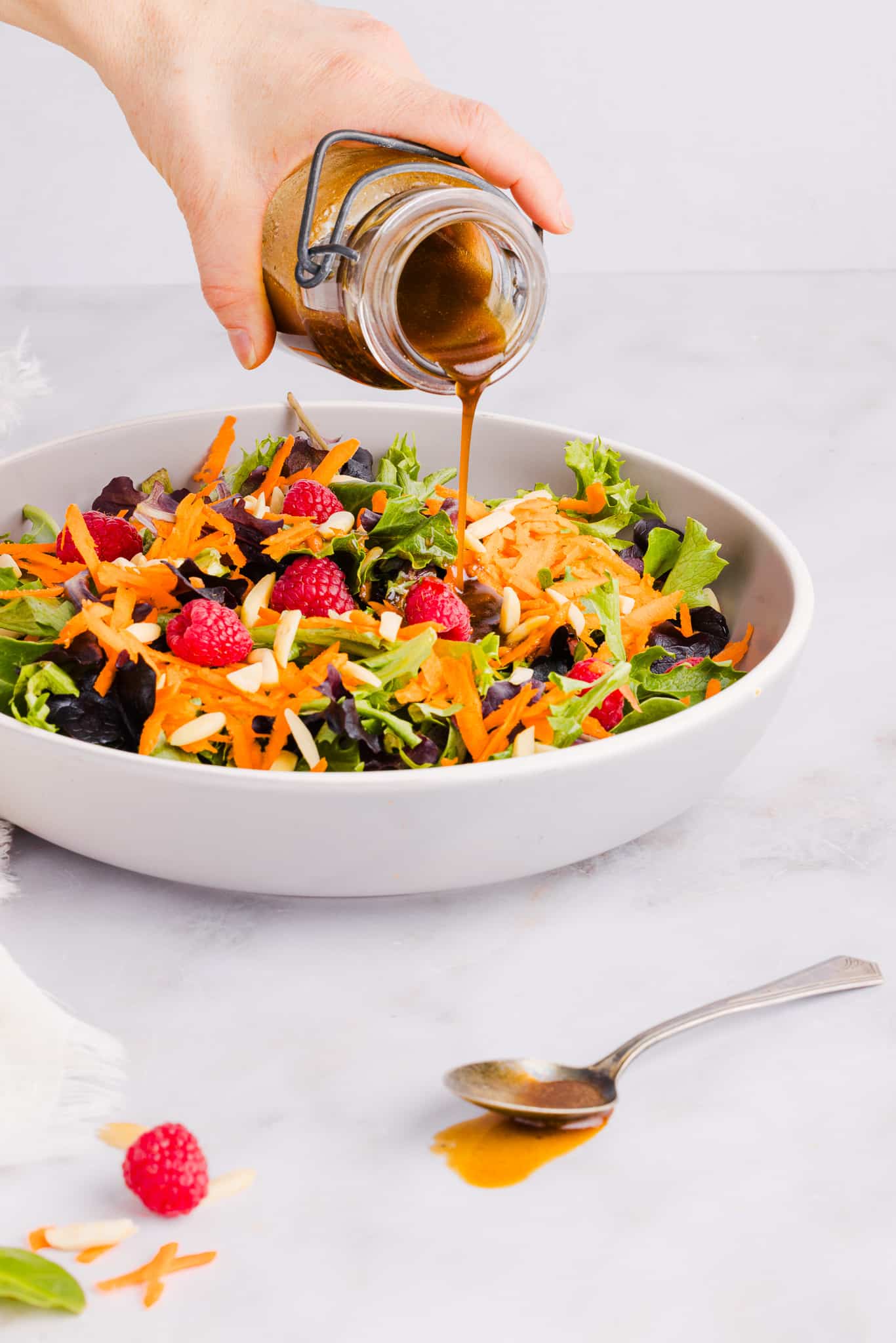 Maple balsamic dressing being poured onto a salad.