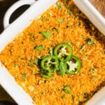 High protein jalapeño popper dip in a white ceramic baking dish, garnished with jalapeños.