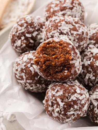 A pile of coconut protein balls with a bite taken out of one of them.