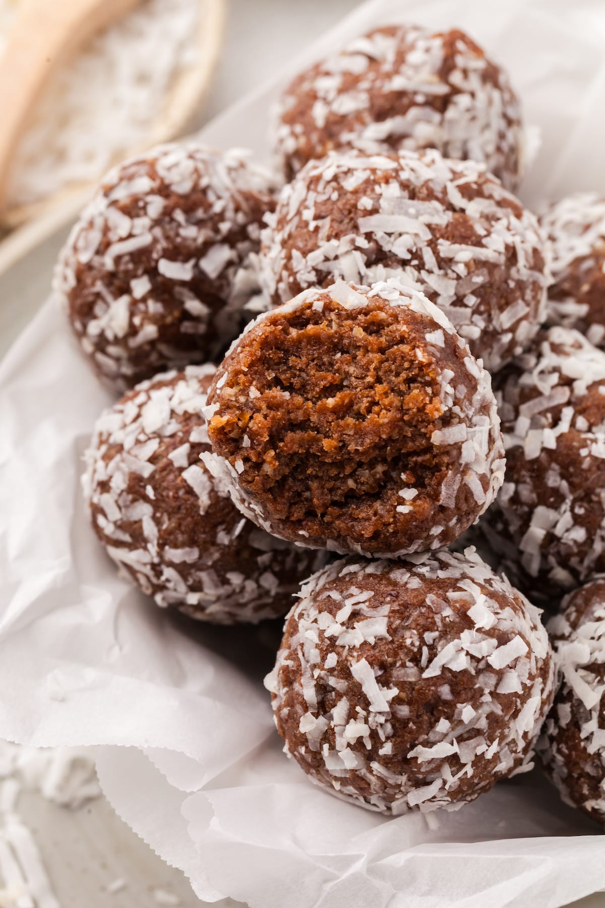 A pile of coconut protein balls with a bite taken out of one of them.